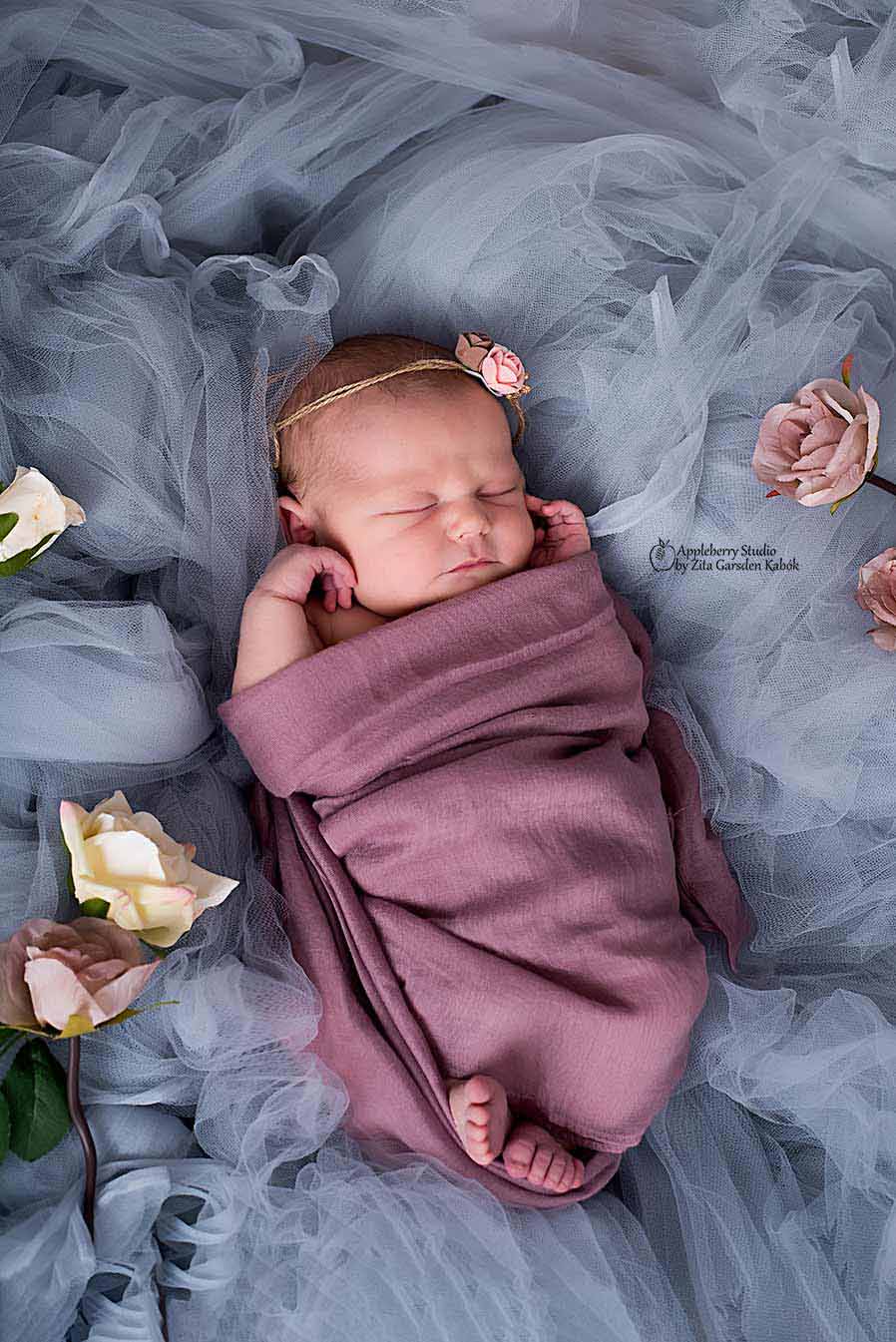 Black and white photo of newborn baby with white backdrop, studio shooting.